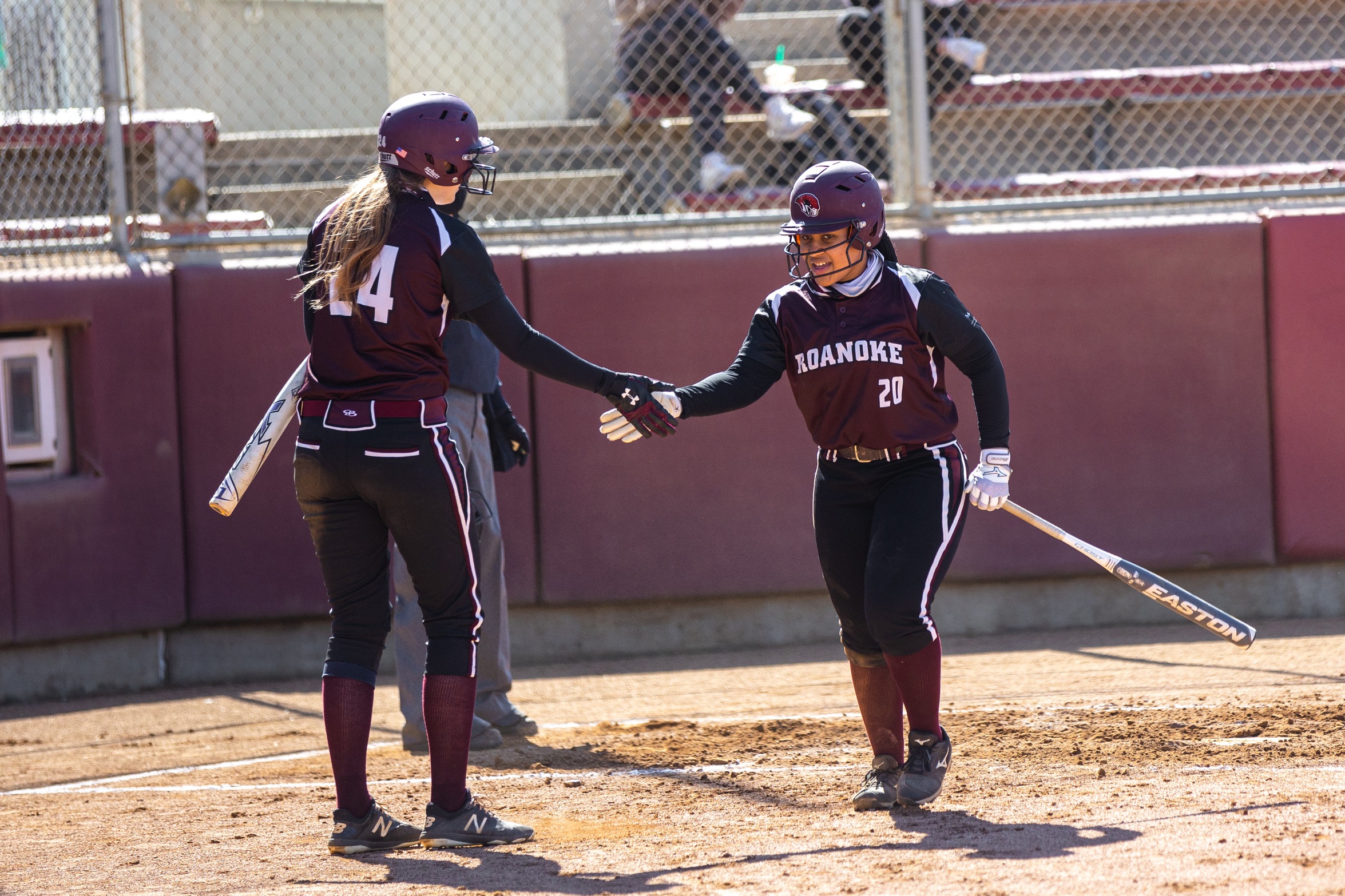 action photo of RC softball players Rebecca Hensley congratulating Janae Henry
