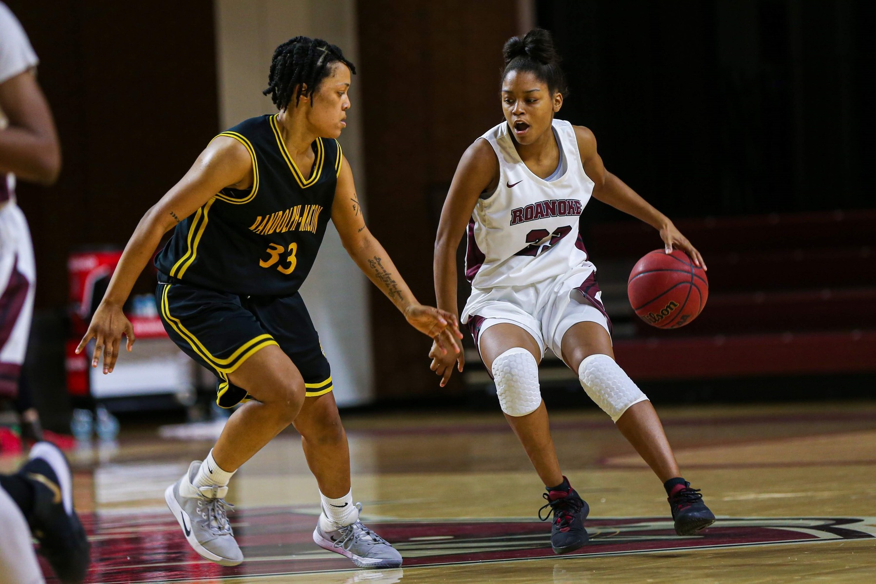 action photo of RC basketball player Ayanna Scarborough dribbling against a defender 