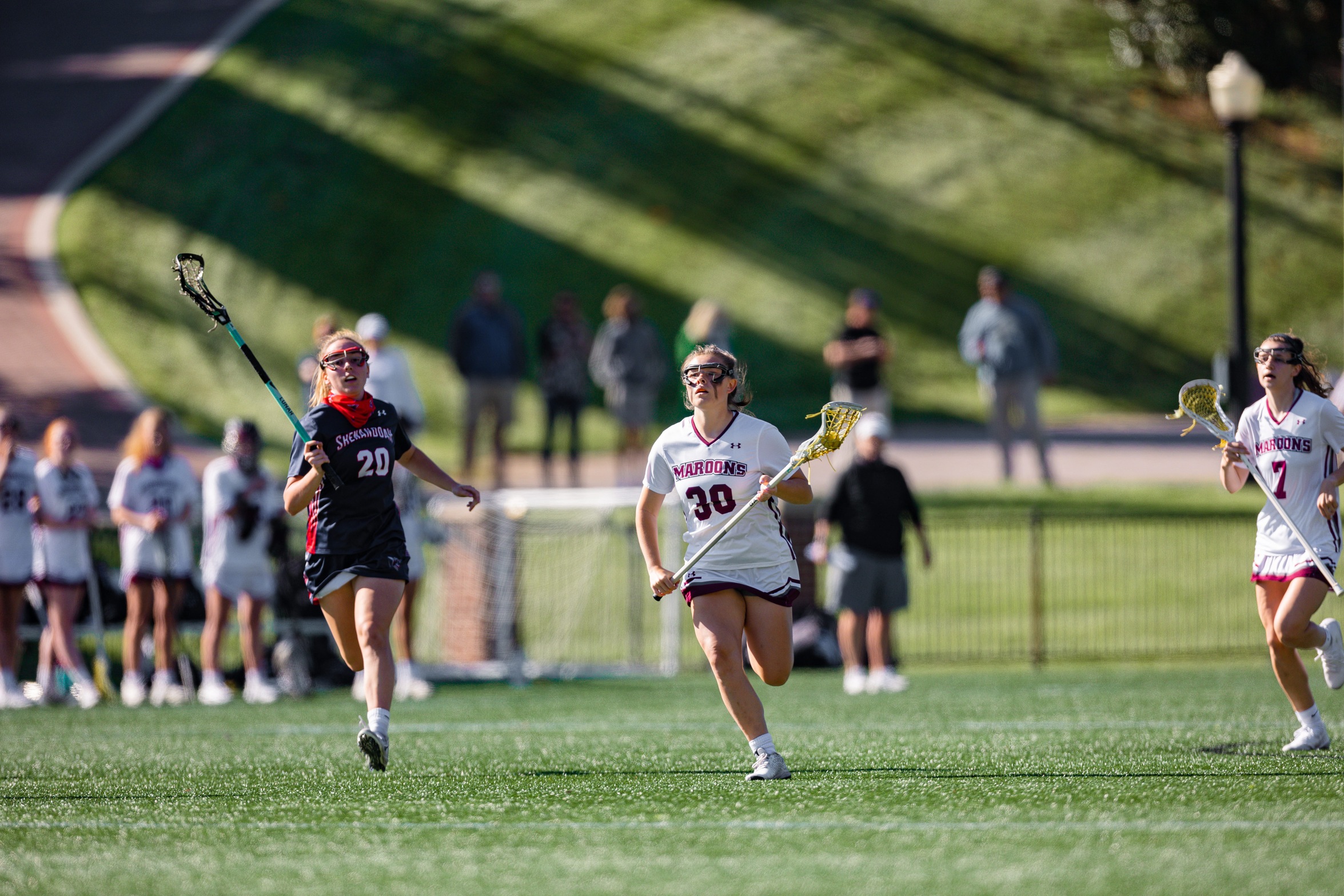 action photo of RC women's lacrosse player Maddie Stopkoski (30) with the ball against a defender