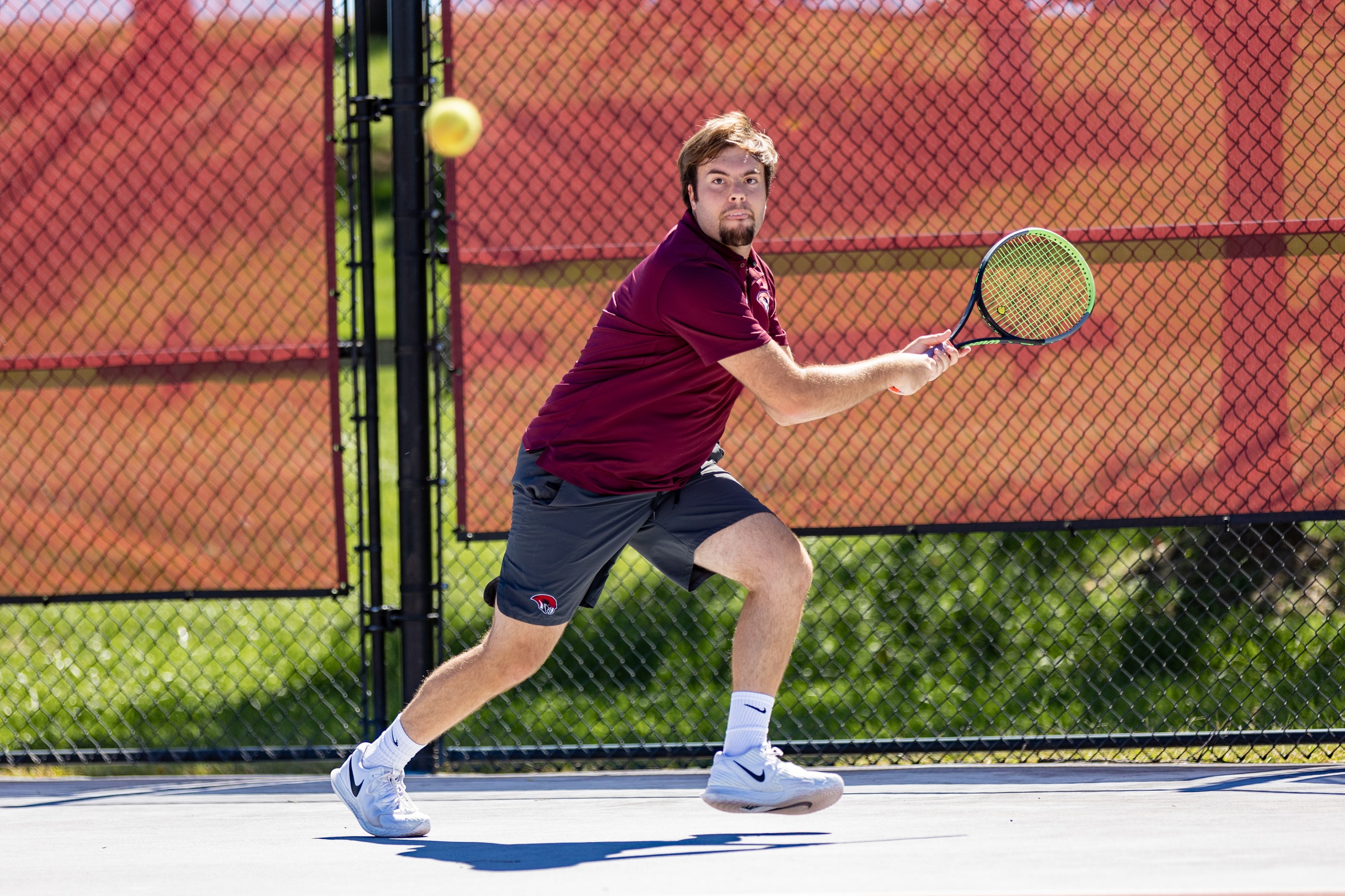 action photo of RC men's tennis player Lance Beheler with a backhand