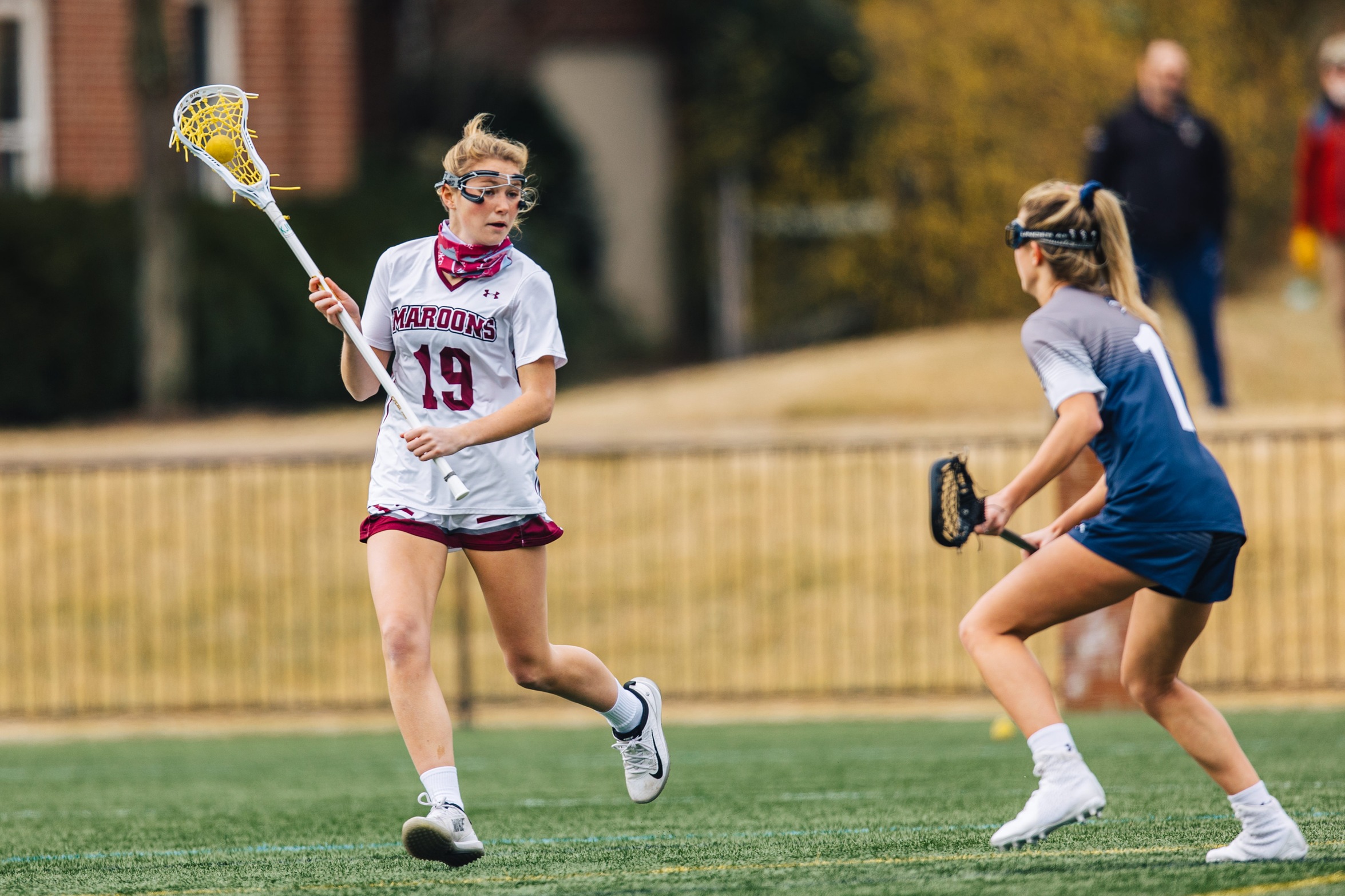 action photo of RC women's lacrosse player Ellie Armstrong handling against a defender