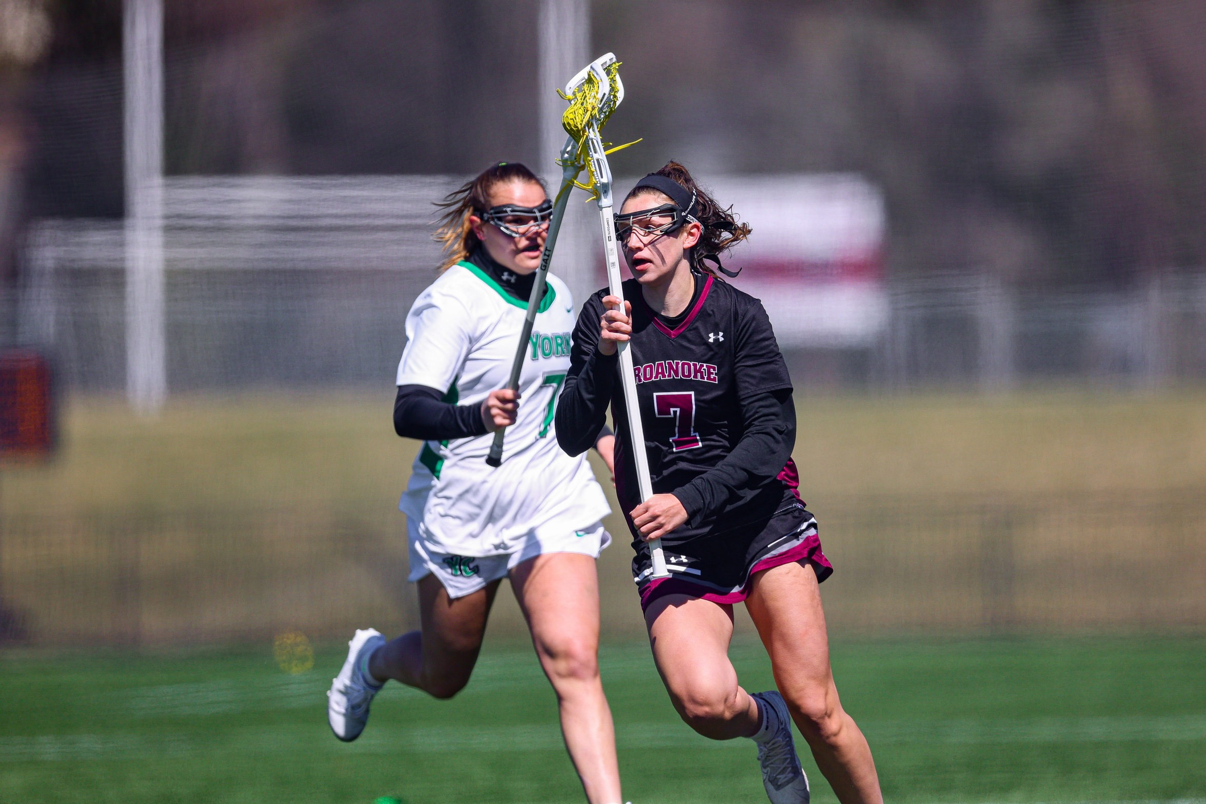 action photo of RC women's lacrosse forward Lilly Blair with the ball against a defender