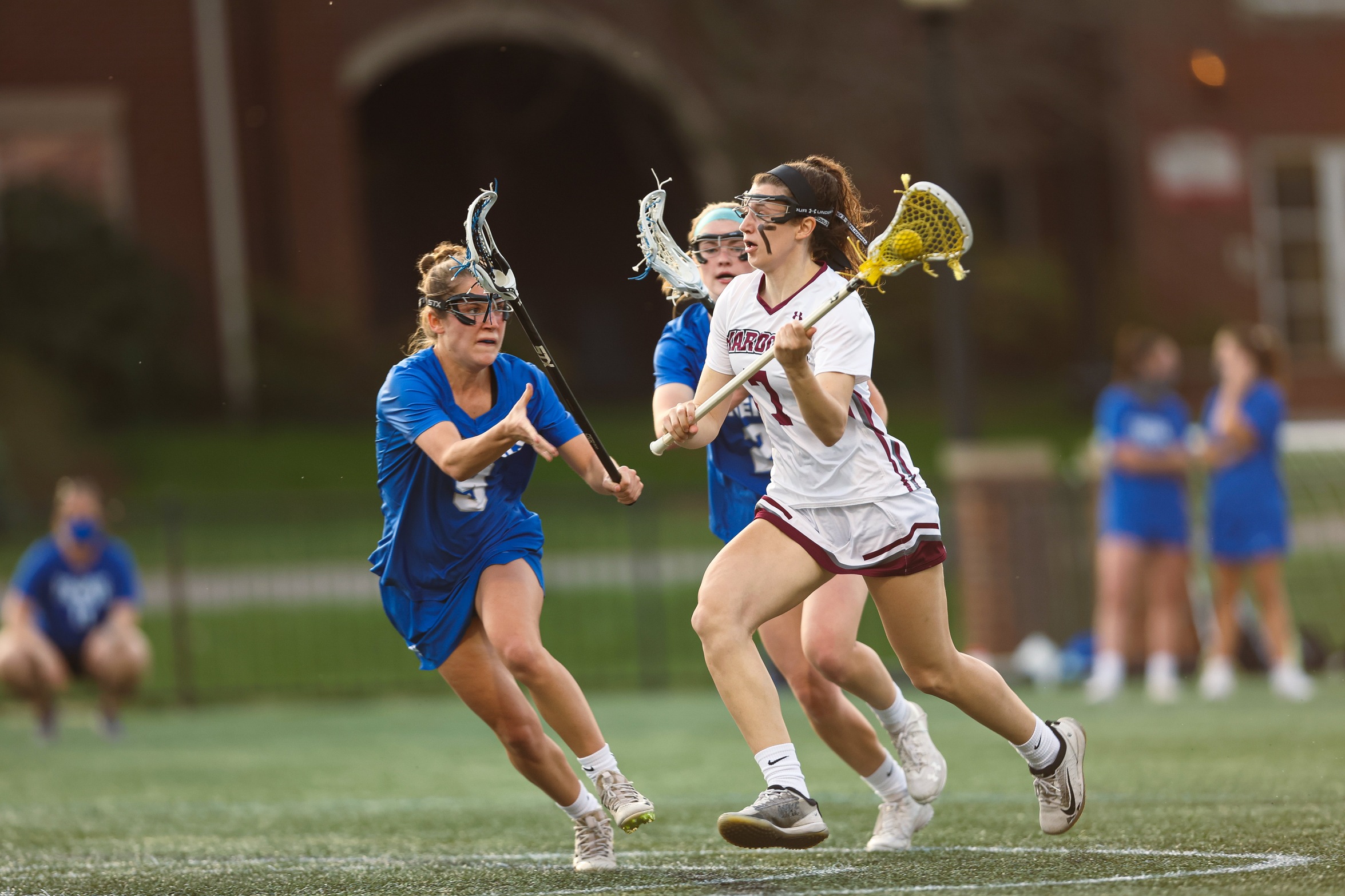 action photo of RC women's lacrosse Lilly Blair with ball against defenders
