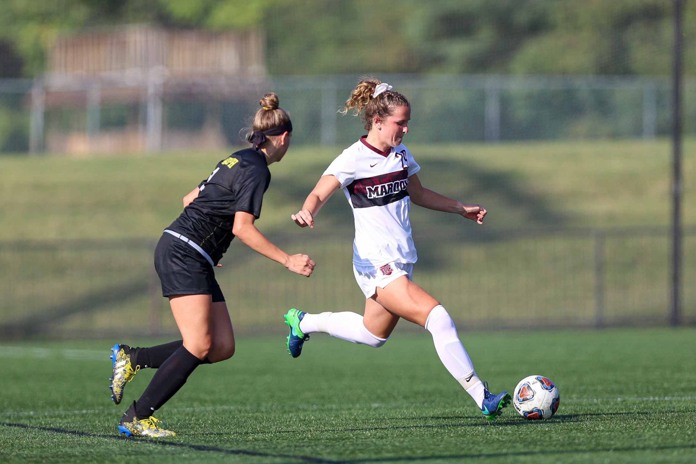 action photo of RC women's soccer player Eliza Ryan kicking the ball past a defender